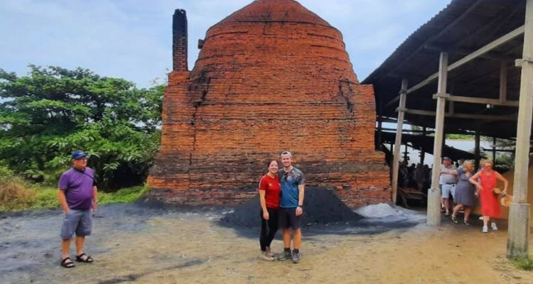 Menschen posieren vor einem großen Ziegelofen.