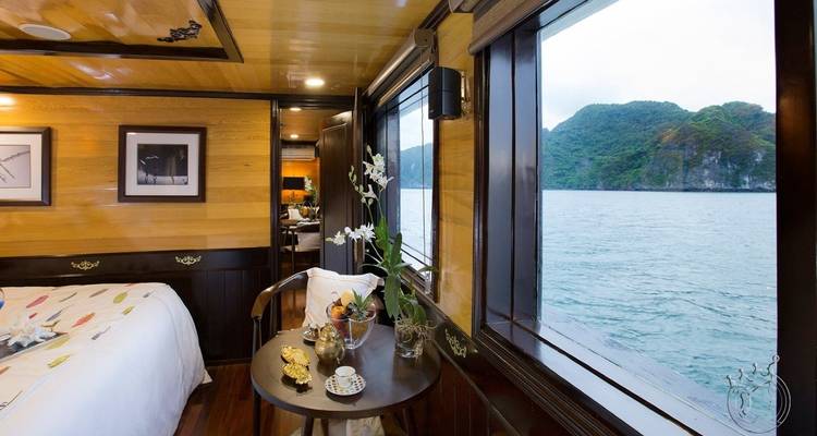 Innenansicht einer Hütte mit einem Bett und Tisch mit Blick auf das Meer.