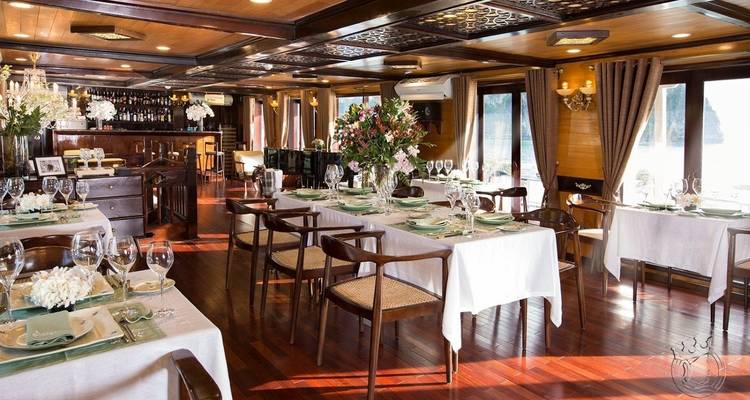 Innenraum eines Speisesaals auf einem Boot mit für Mahlzeiten gedeckten Tischen.