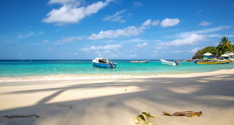 Boats anchored in a clear turquoise ocean with a sandy beach.