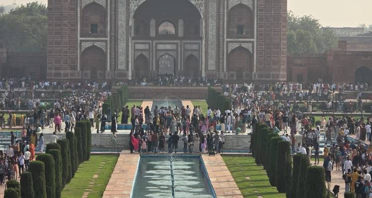 Grote menigte verzamelen zich langs de spiegelende vijvers die naar de sierlijke hoofdpoort van het Taj Mahal-complex kijken.