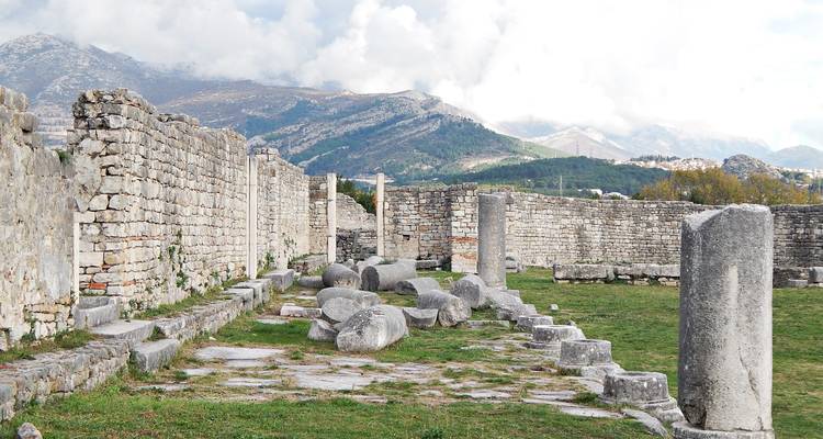 Alte Steinmauern und verstreute Säulen mit rauen Bergen in der Ferne in Salona
