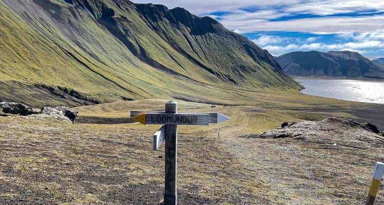 Wandelpaalbord dat naar Lödmundur wijst met vulkanische bergen en meer op de achtergrond.