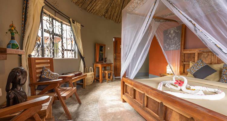 Interior of a room with wooden furniture and mosquito netted bed.