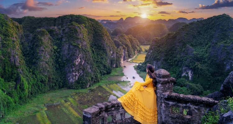 Woman in a vibrant dress enjoying a scenic view of a valley in Ninh Binh.