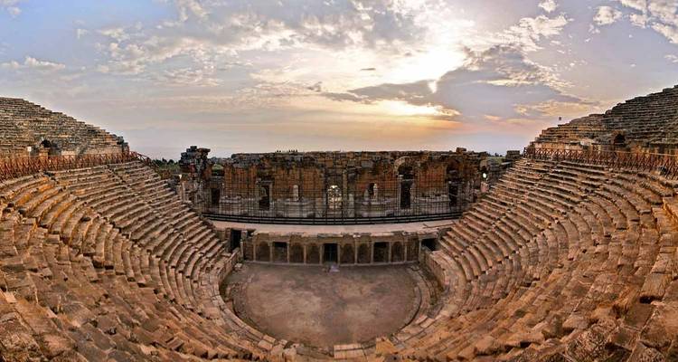 Ein antikes Amphitheater mit klarem Himmel bei Sonnenuntergang.