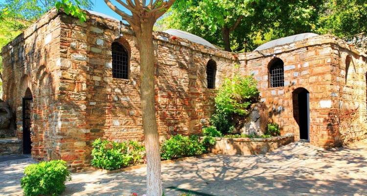 Historisches Gebäude umgeben von Bäumen und Grün.