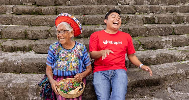 Two people laughing and sitting on stone steps, in traditional attire.