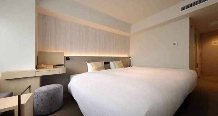 Modernes Hotelzimmer mit einem großen Bett und minimalistischem Design.