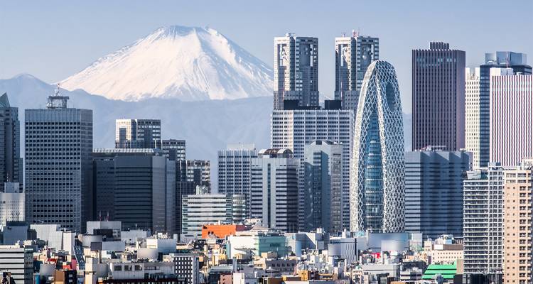 Skyline de una ciudad con un edificio moderno distintivo y el Monte Fuji al fondo.