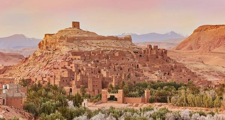 Alte Lehmziegelstadt auf einem Hügel unter einem Sonnenuntergangshimmel.