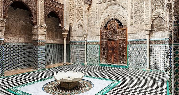Ingewikkelde binnenplaats met mozaïektegels en centrale fontein.