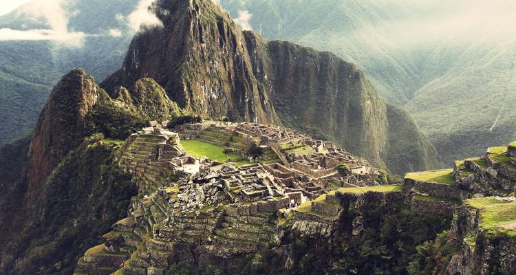 Machu Picchu met weelderige groene terrassen en bergen.