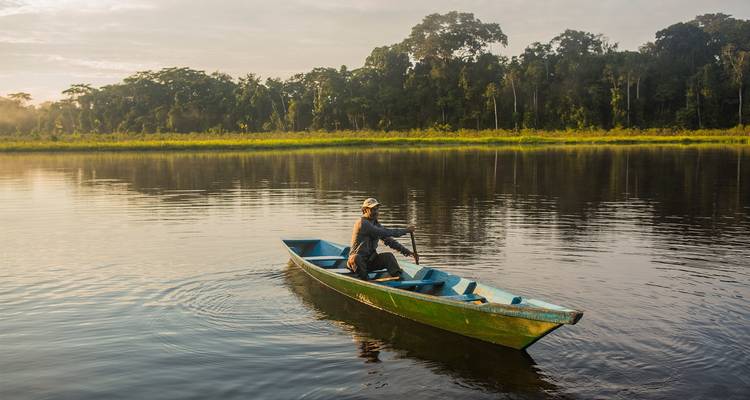Mann, der ein Kanu auf einem abgelegenen Dschungelfluss paddelt.