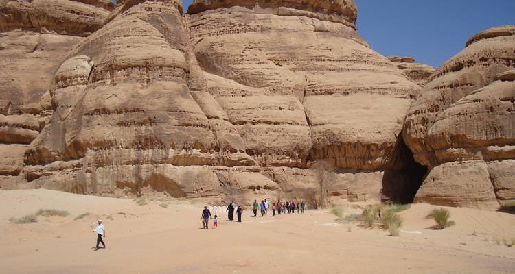 A group of people walking through desert rock formations.