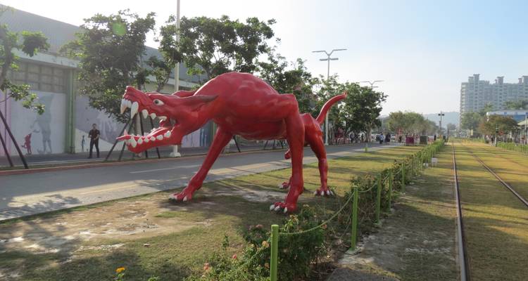 Sculptuur van een rood wezen in een park.