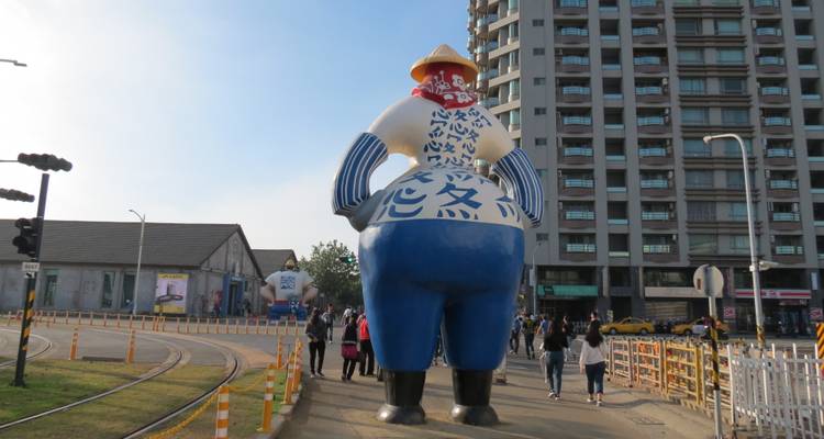 Grote mascotte sculptuur met stadsachtergrond.