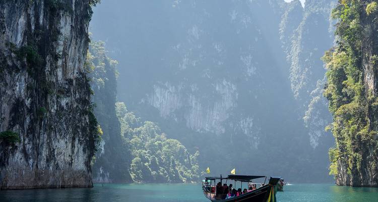 Bateau à longue queue sur un lac calme entouré de falaises à Khao Sok.