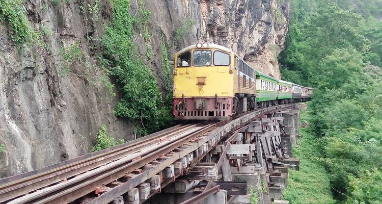 Zug fährt auf einem Bahngleis an einer Klippe.