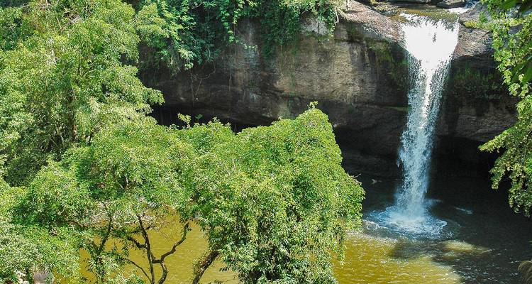 Tropische waterval die in een groen meer stort, omgeven door dicht jungleoerwoud in het Khao Yai Nationaal Park.