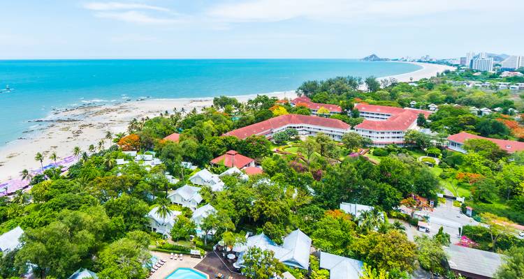 Resort mit Blick auf den Strand mit grünen Gärten und weißen Bungalows.