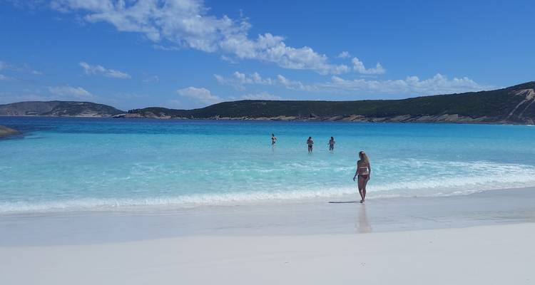 Menschen genießen einen Tag am Strand mit klarem blauen Wasser.