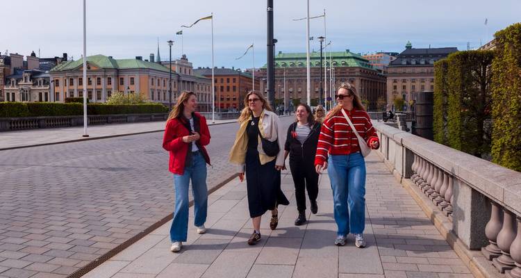 Un groupe de jeunes femmes se promène sur un pont de pierre bordé de drapeaux au centre-ville de Stockholm.