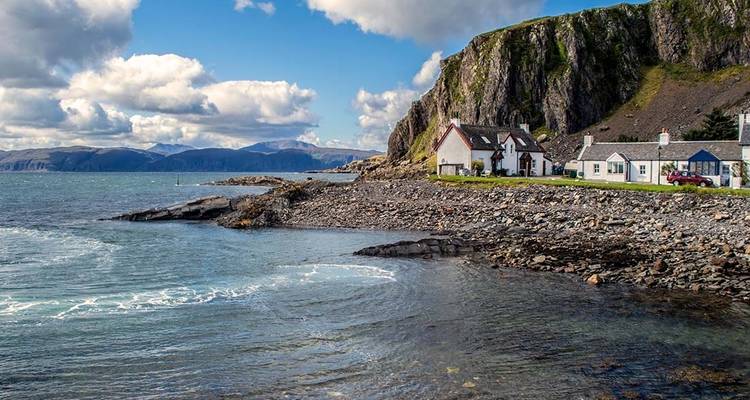 Küstenlandschaft mit felsigen Ufern und kleinen Häusern.