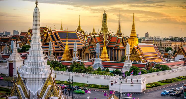 Grand Palace in Bangkok, ornate architecture under a golden sky.