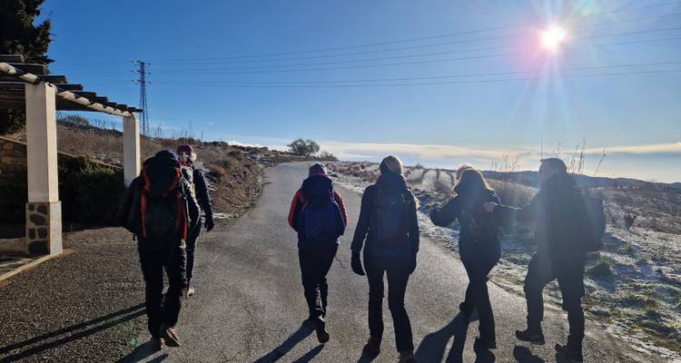 Een groep wandelaars die op een pad lopen met een zonnige hemel erboven.
