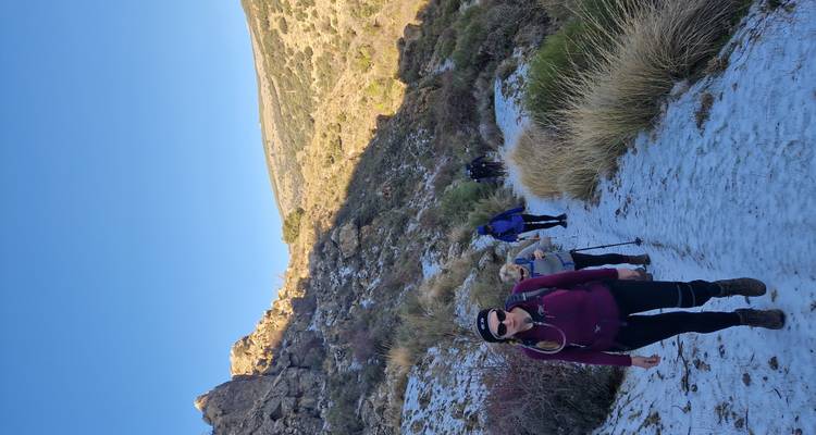 Wandelaars die een smal pad opgaan tussen rotsachtige heuvels.