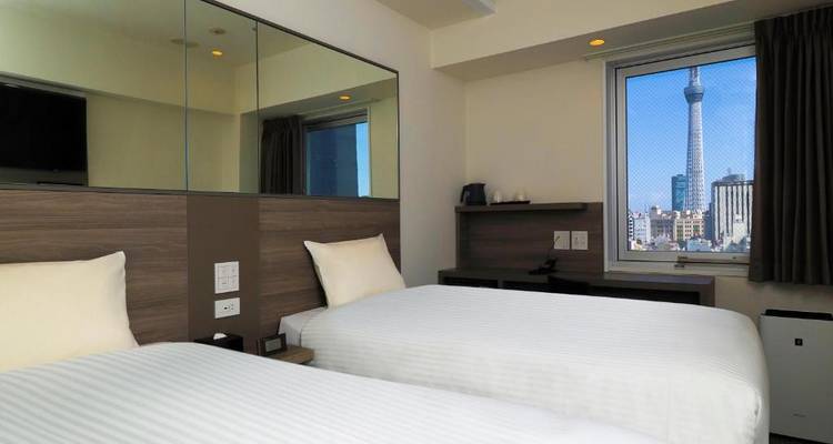 Hotelzimmer mit zwei Betten und Blick auf einen Stadtturm.