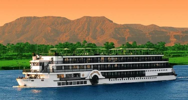 Kreuzfahrtschiff, das auf einem Fluss mit Bergen im Hintergrund segelt