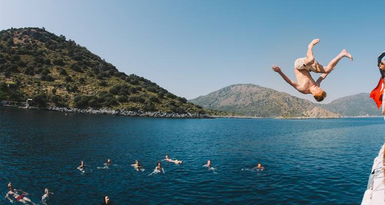 Personne faisant un salto arrière dans l'océan avec d'autres personnes qui nagent.