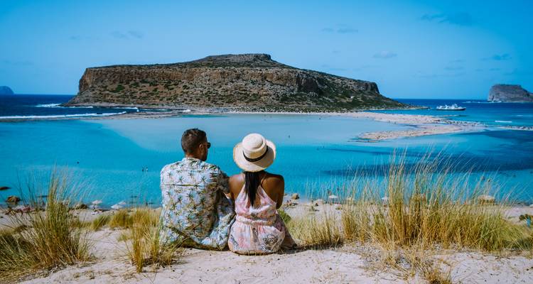 Pareja sentada contemplando una zona de playa pintoresca.