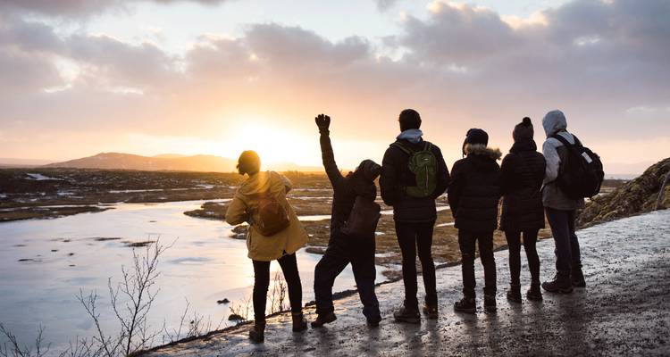 Groupe de personnes regardant le coucher de soleil sur un paysage gelé