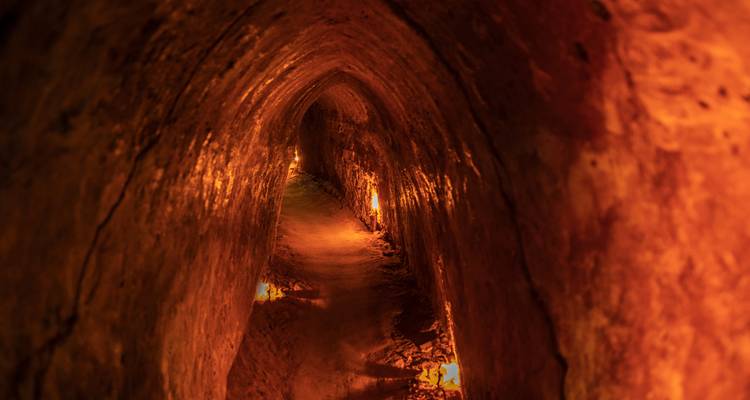 Dimly lit underground tunnel with candles on sides.