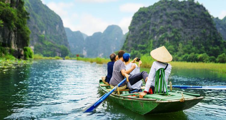 People in a boat on a river with mountains in the background.