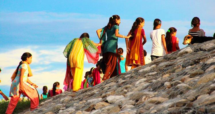 Children in colorful clothing climbing up a rocky slope.