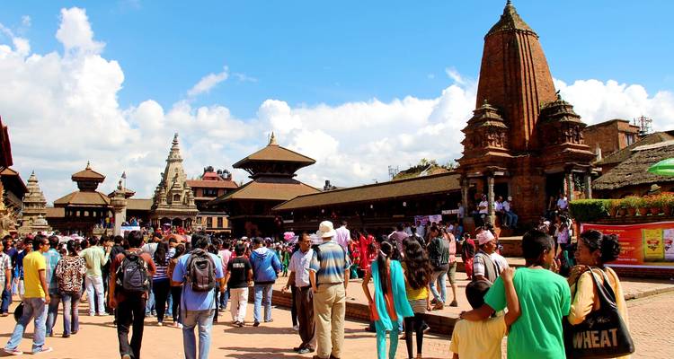 A busy square with traditional Nepalese architecture and a crowd of people.