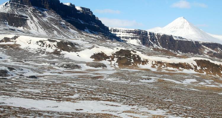 A snowy, mountainous landscape with rugged terrain and clear skies.