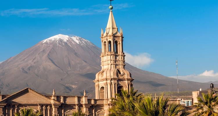A tower with a mountain in the background, under a clear blue sky