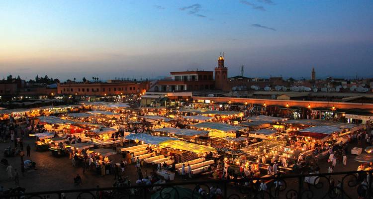 Marktplatz in Marrakesch bei Sonnenuntergang mit bunten Ständen und Menschen