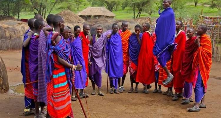 Groupe de personnes Maasaï en tenue traditionnelle, l'une d'entre elles sautant.
