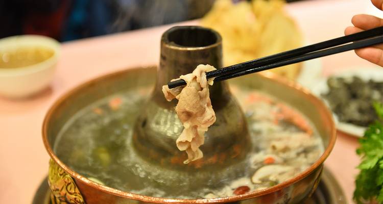 "Plat de fondue chinoise avec des baguettes qui saisissent de la nourriture."
Alternative translation: "Hot pot avec des baguettes pour prendre les aliments."
Note: "Hot pot" is sometimes kept as is in French since it's a well-known term, but "fondue chinoise" is the more traditional French translation.