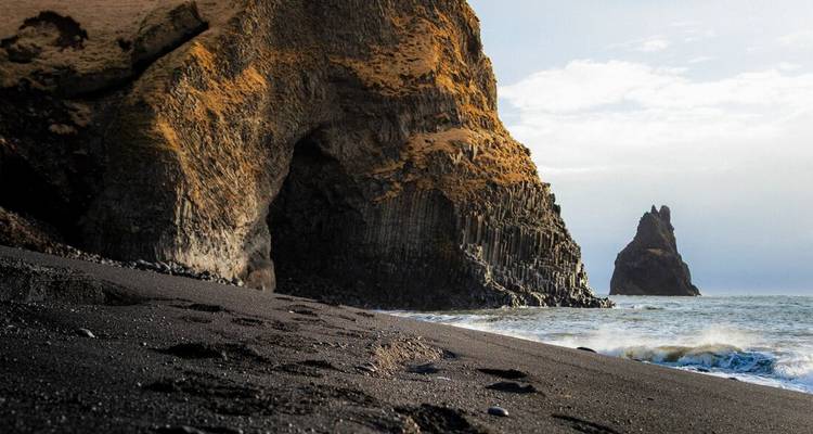 Zwart zandstrand met basaltgrot en Reynisdrangar zeestapel bij Vik.