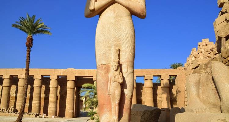 Antike Statue und Säulen unter einem klaren blauen Himmel.