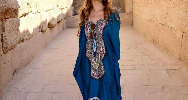 Frau in einem blauen Kleid, die in einem antiken Korridor steht.