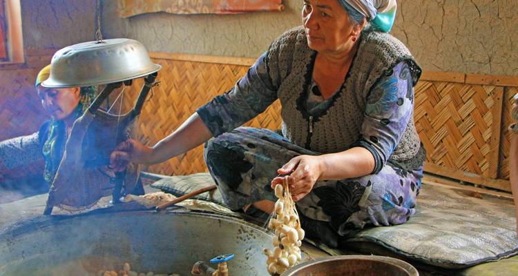 A woman making dairy products in a traditional setting.