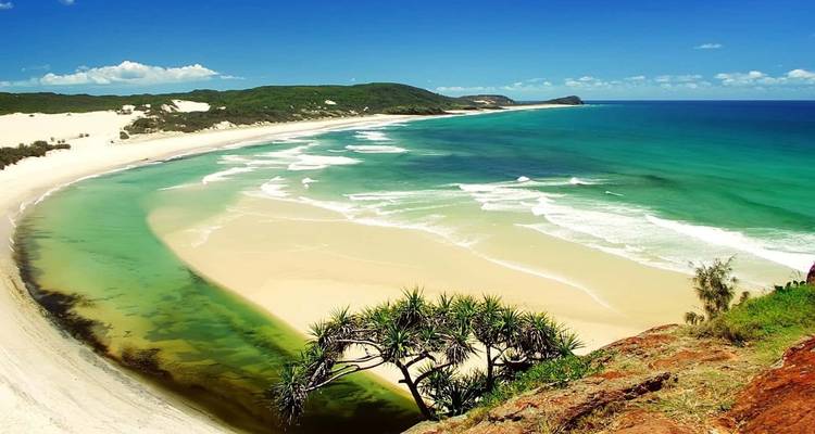 Breed zandstrand met turquoise water en heldere lucht.